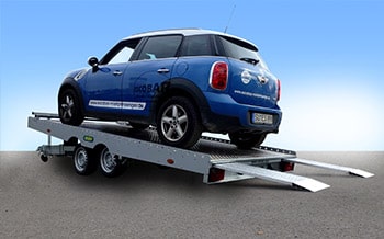 Blauer Mini auf kippbarem Autotransporter auf Straße